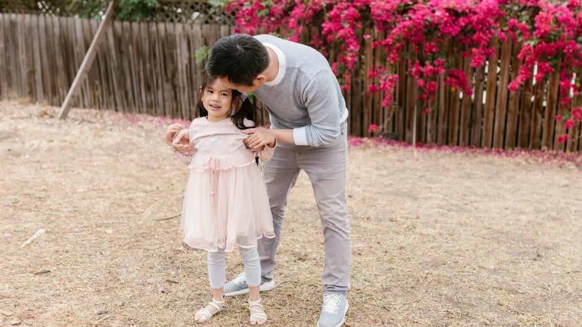 A father shares a joyful moment with his daughter in a blooming garden with vibrant flowers.