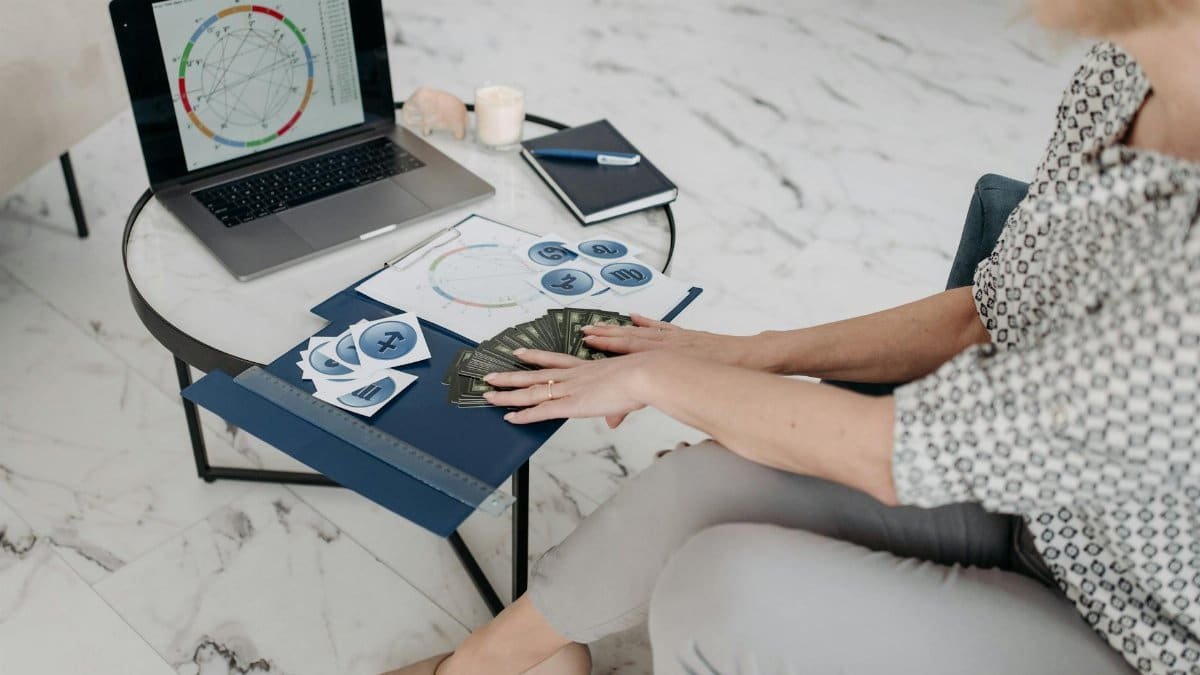 Astrology scene with a woman using a laptop and tarot cards in a modern living room.