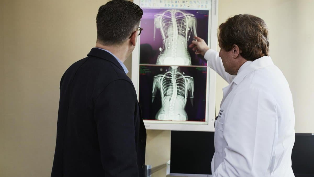 A doctor explains X-ray results to a patient in a clinical setting, highlighting healthcare communication.
