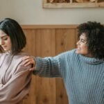 Two young women in a serious discussion in a cozy room setting.