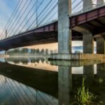 Peaceful reflection of Pitt River Bridge in Pitt Meadows, BC, during sunrise.