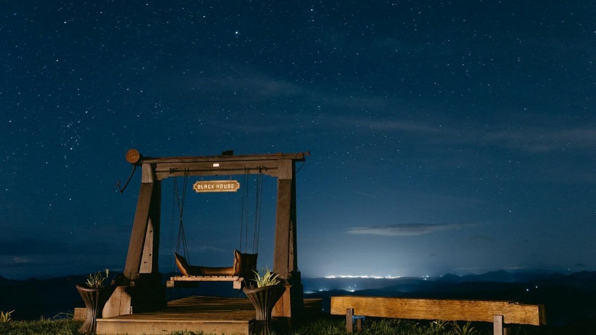A tranquil wooden swing under a starry sky in Santa Teresa, Brazil.