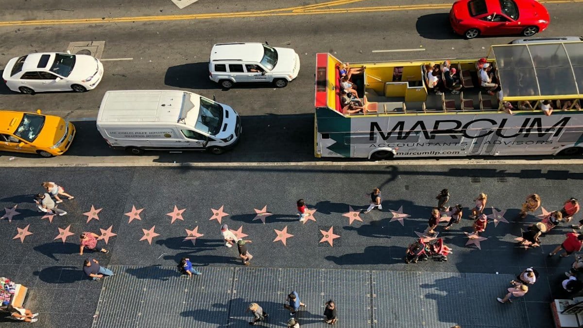 Bird's-eye view of Hollywood Walk of Fame with tourists and vehicles on a sunlit afternoon.