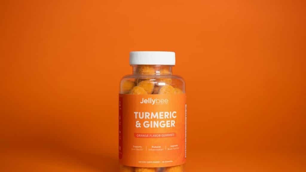 Bright image of Jellybee Turmeric & Ginger gummies in a plastic bottle against an orange backdrop.