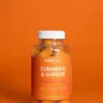 Bright image of Jellybee Turmeric & Ginger gummies in a plastic bottle against an orange backdrop.