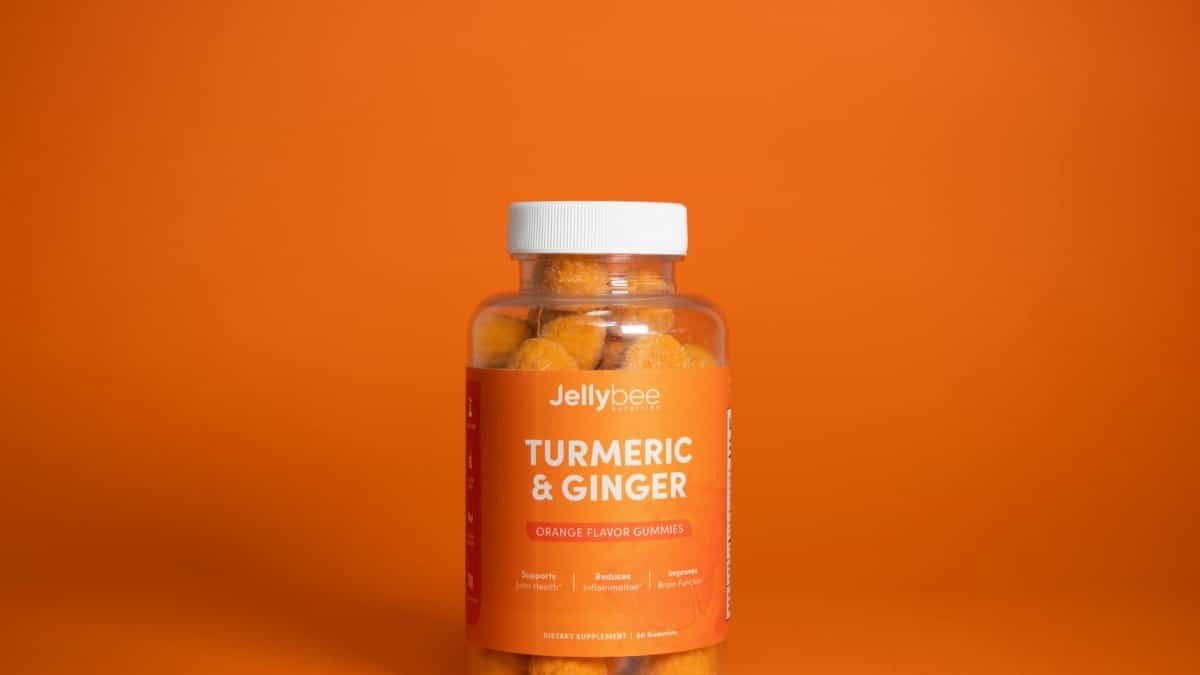 Bright image of Jellybee Turmeric & Ginger gummies in a plastic bottle against an orange backdrop.