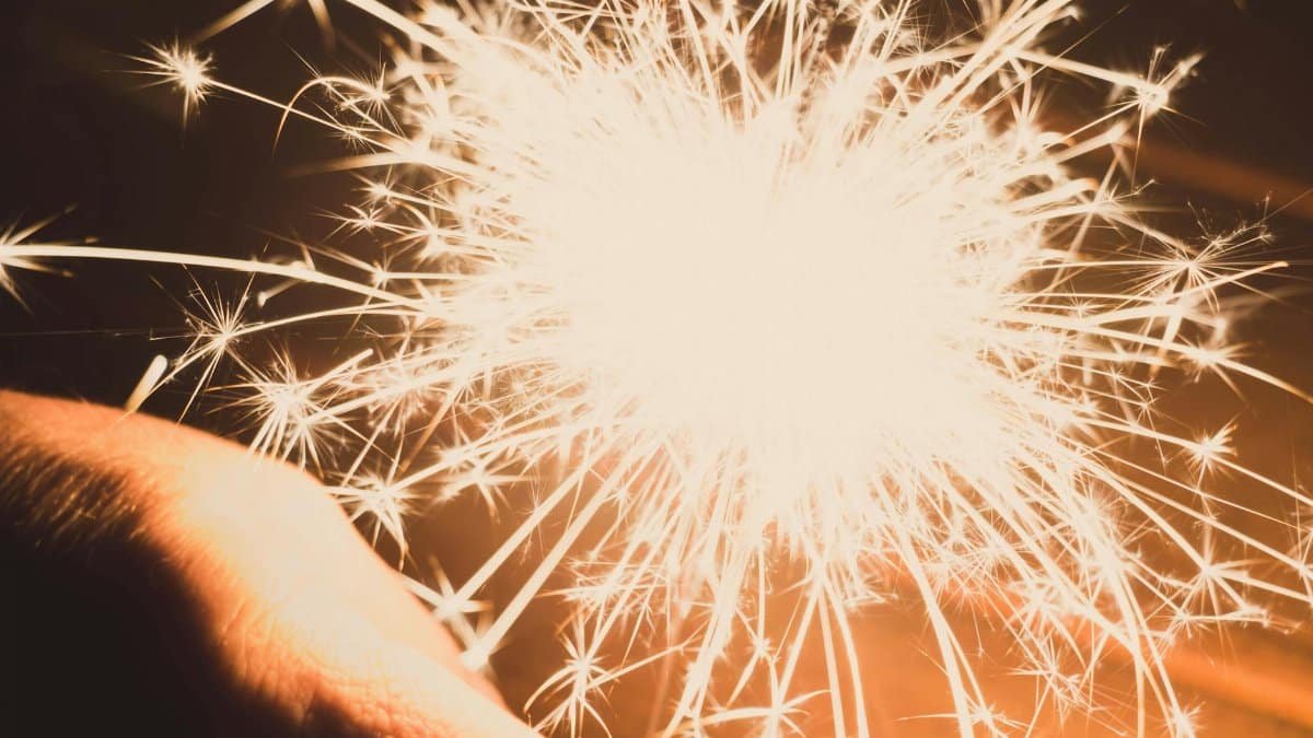 A captivating close-up image of a bright sparkler emitting dazzling sparks against a warm background.