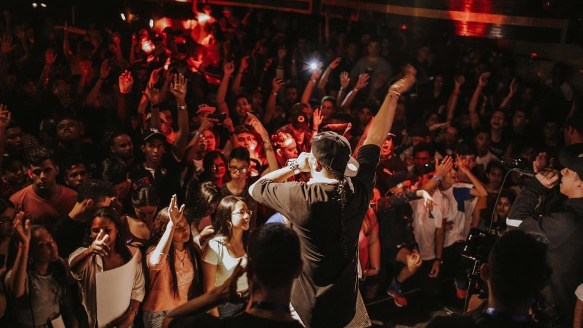 Vibrant rap concert with lively crowd and dynamic stage performance in a bustling nightclub atmosphere.