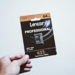 A hand holding a packaged 64GB Lexar Professional SD card, ideal for digital storage.