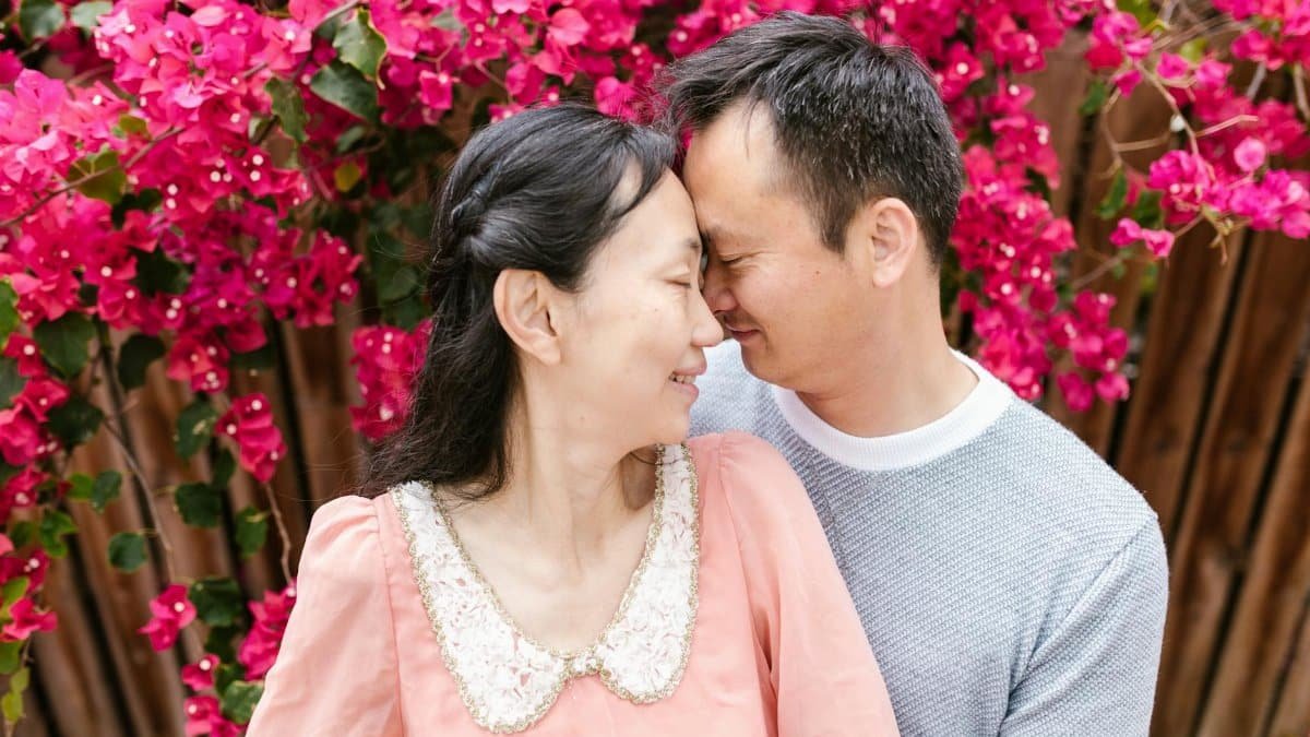 A couple joyfully sharing an intimate moment surrounded by vibrant flowers.