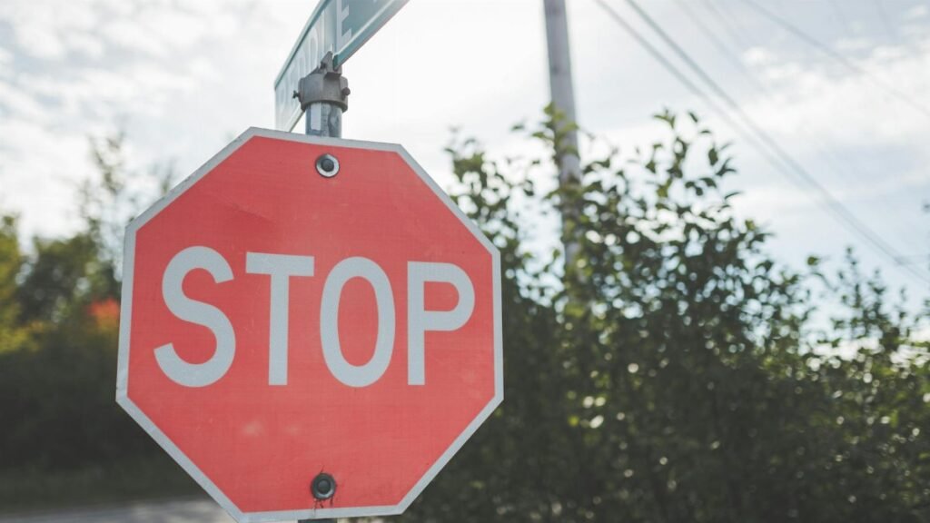 A red stop sign on a pole against a blue sky with light clouds. Outdoor scene.