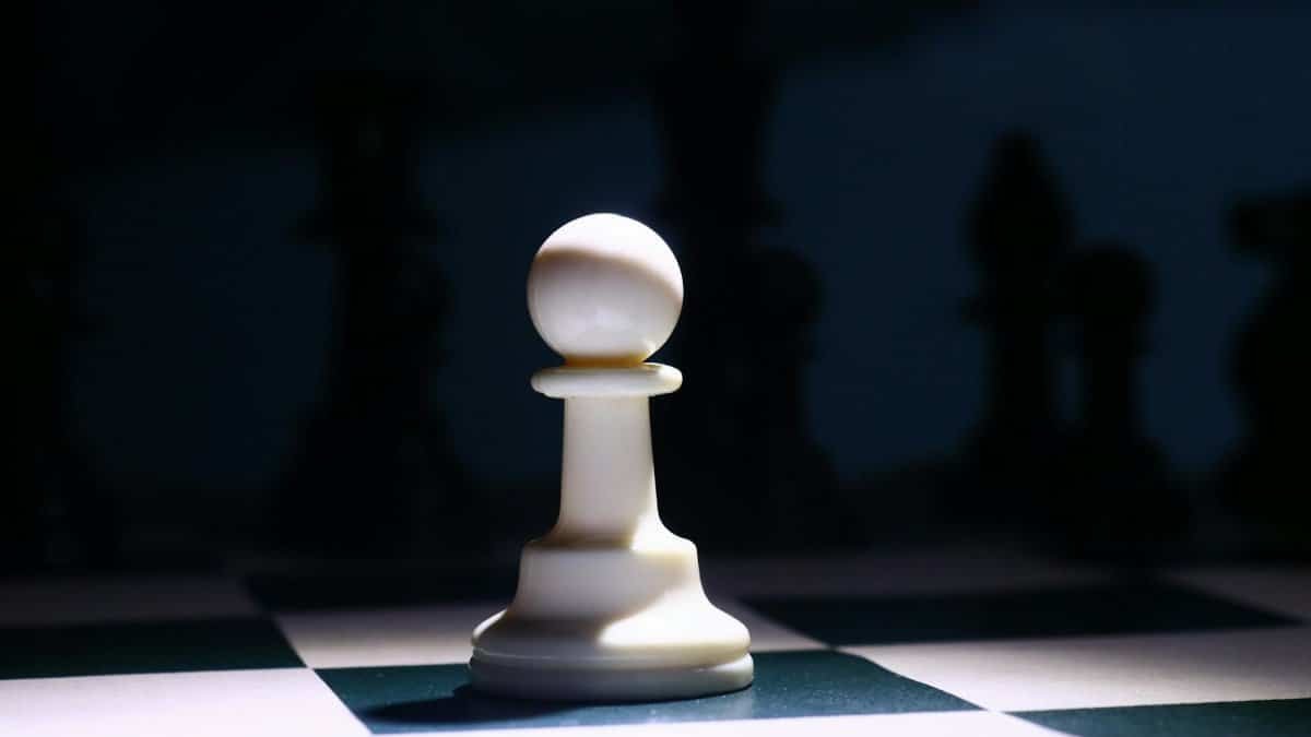 Close-up of a white chess pawn highlighted dramatically on a chessboard, depicting strategy and focus.
