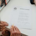 A close-up shot of two people signing a divorce decree at a law office table.