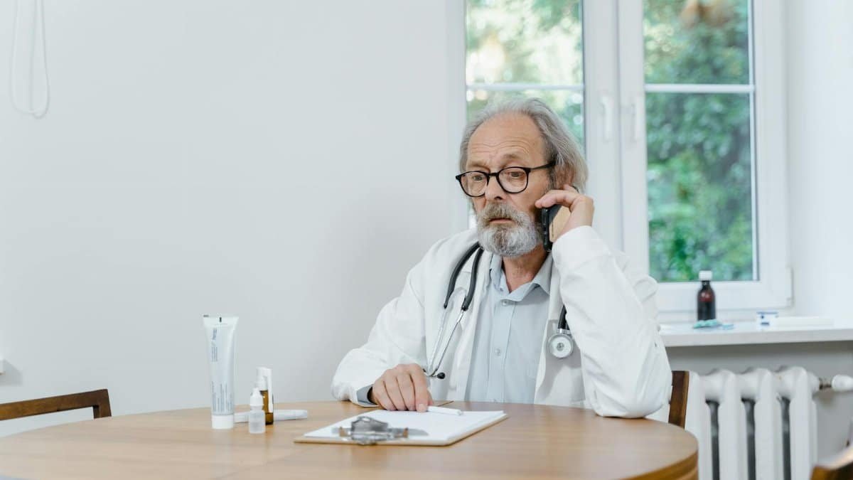 A senior doctor making a telemedicine call in an office setting, discussing medical cases.