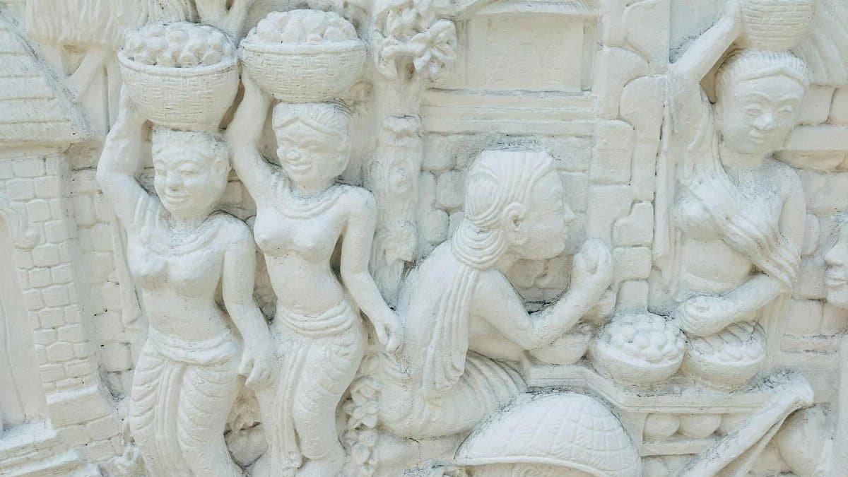 Detailed ancient bas relief sculpture depicting traditional life scenes in finely carved stucco artwork.