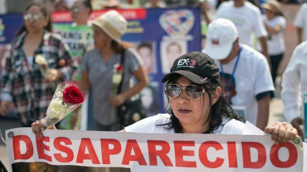 Demonstrators in Mexico rally for missing people, holding banners and red roses.
