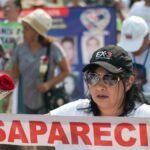 Demonstrators in Mexico rally for missing people, holding banners and red roses.