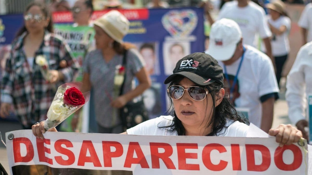 Demonstrators in Mexico rally for missing people, holding banners and red roses.