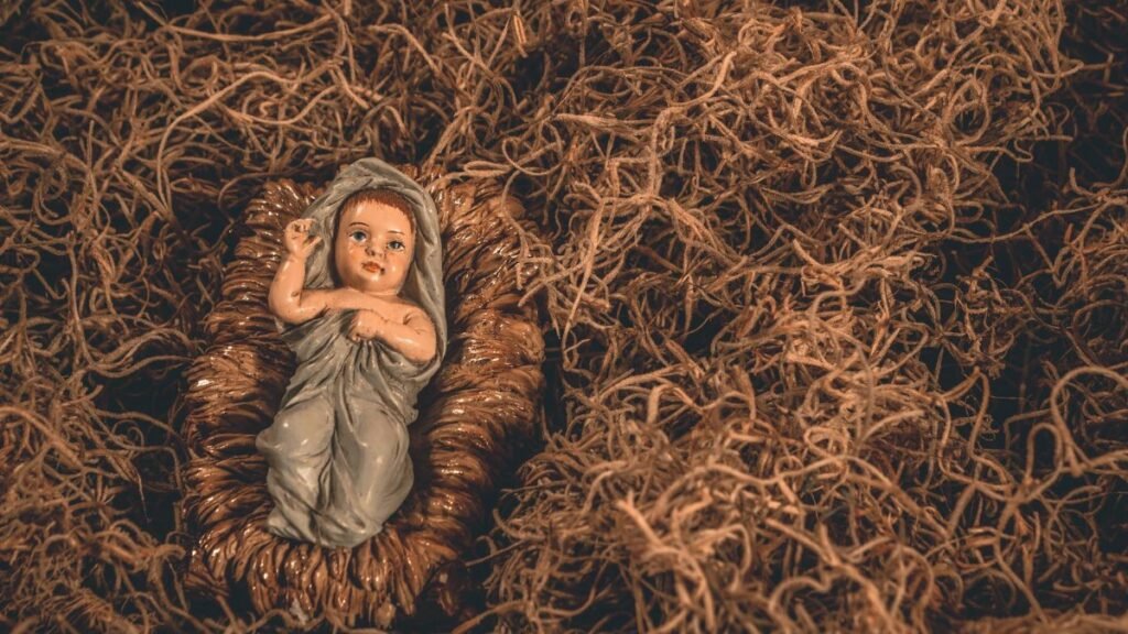 A nativity scene featuring a baby Jesus figurine surrounded by straw, symbolizing hope and tradition.
