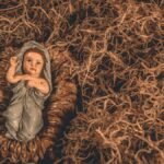 A nativity scene featuring a baby Jesus figurine surrounded by straw, symbolizing hope and tradition.