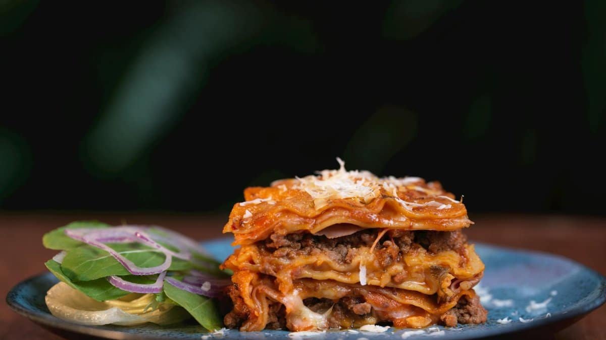 A mouth-watering slice of traditional Italian lasagna served with a side of fresh salad.