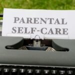 A vintage typewriter showcasing a "Parental Self-Care" message on paper outdoors.