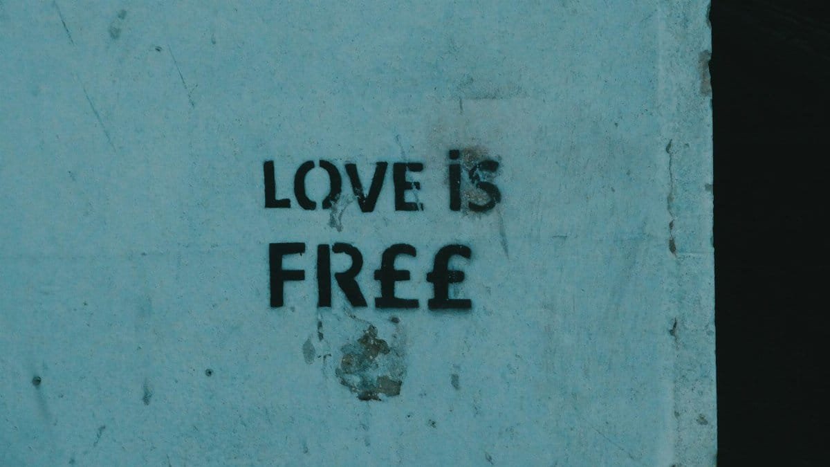 Graffiti artwork with 'Love is Free' message on a concrete wall, symbolizing freedom and expression.