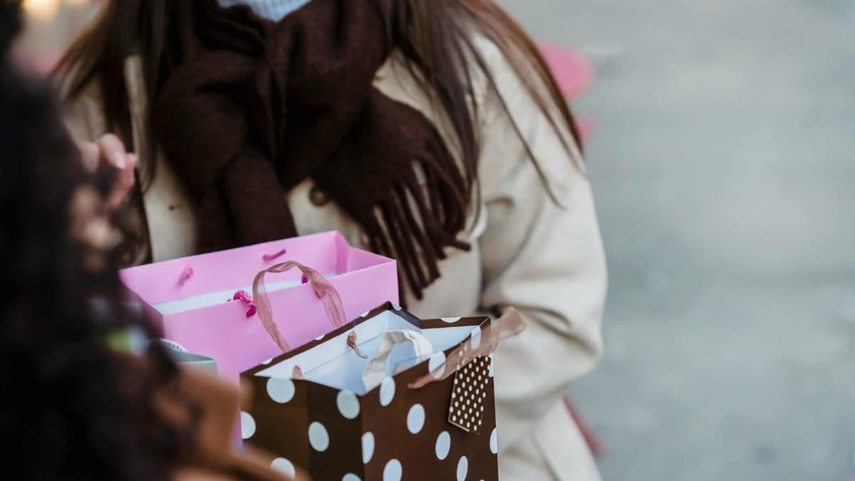Two women shopping together with colorful bags capturing the festive spirit outdoors.