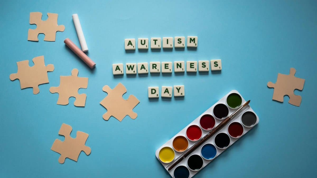 Colorful autism awareness concept with puzzle and watercolor set on a blue background.