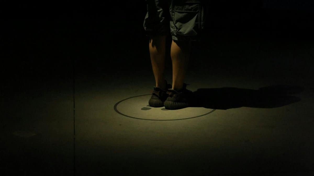 Close-up of legs in dark spotlight, creating a mysterious and dramatic atmosphere.