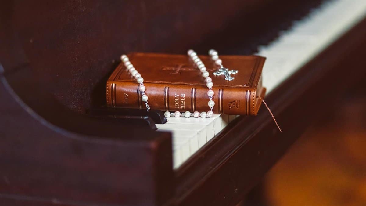 A Bible and rosary resting on a piano, symbolizing faith and music harmony.