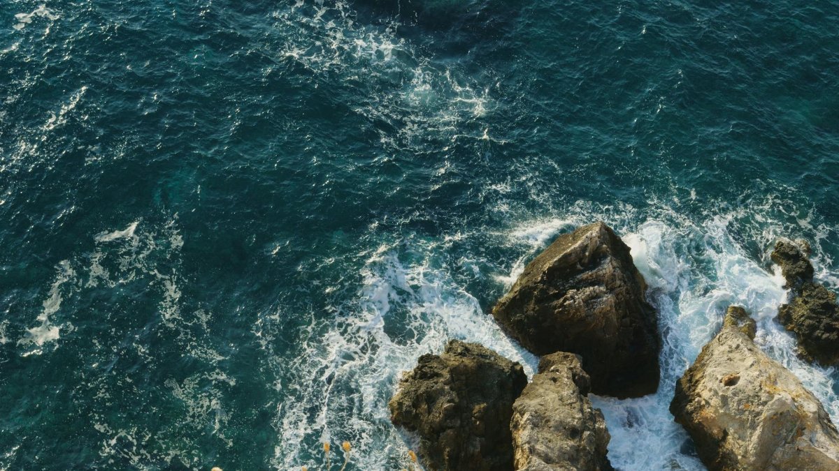 A beautiful aerial shot of crashing waves against rocks in the Adriatic Sea near Italy, perfect for travel and nature themes.