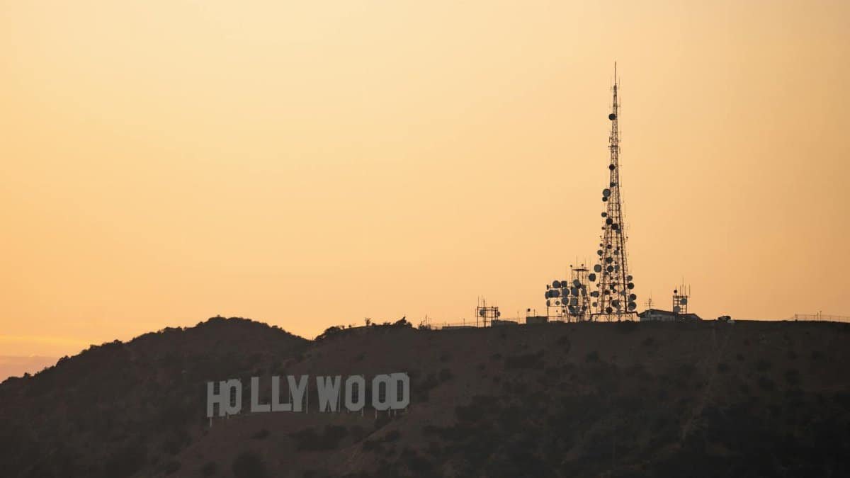 Silhouette of Hollywood Sign and communication tower against the golden hour sky in Los Angeles.