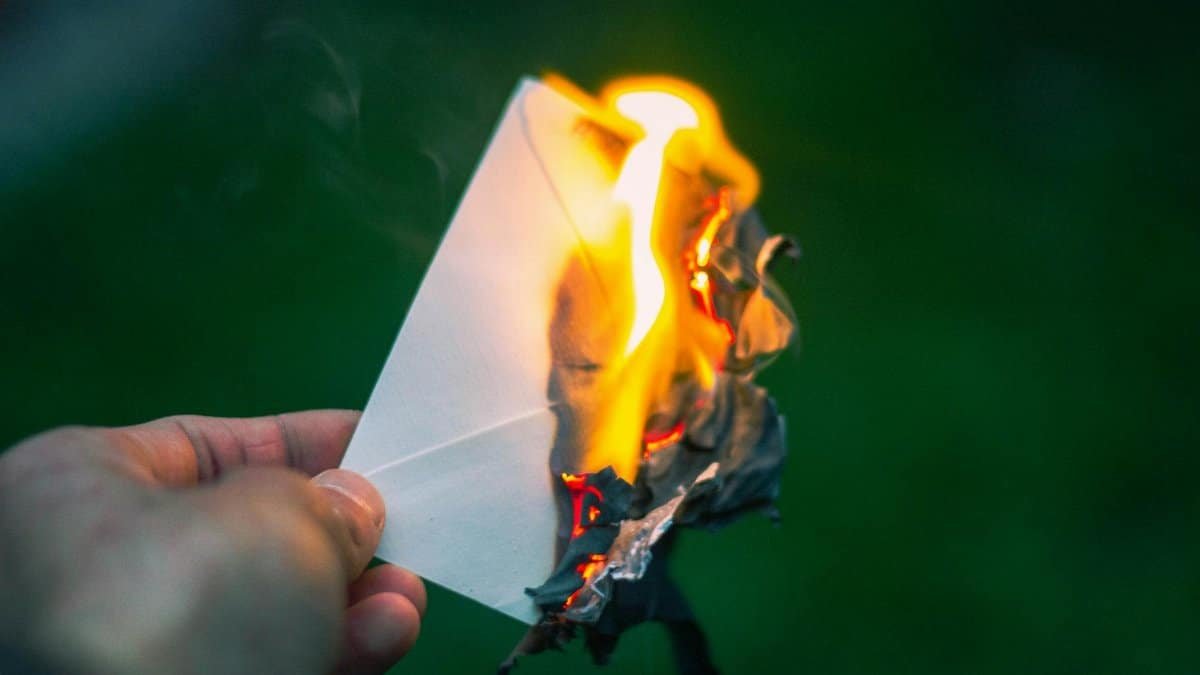 A captivating image of a hand holding a burning paper, symbolizing destruction or release. Perfect for themes of letting go.