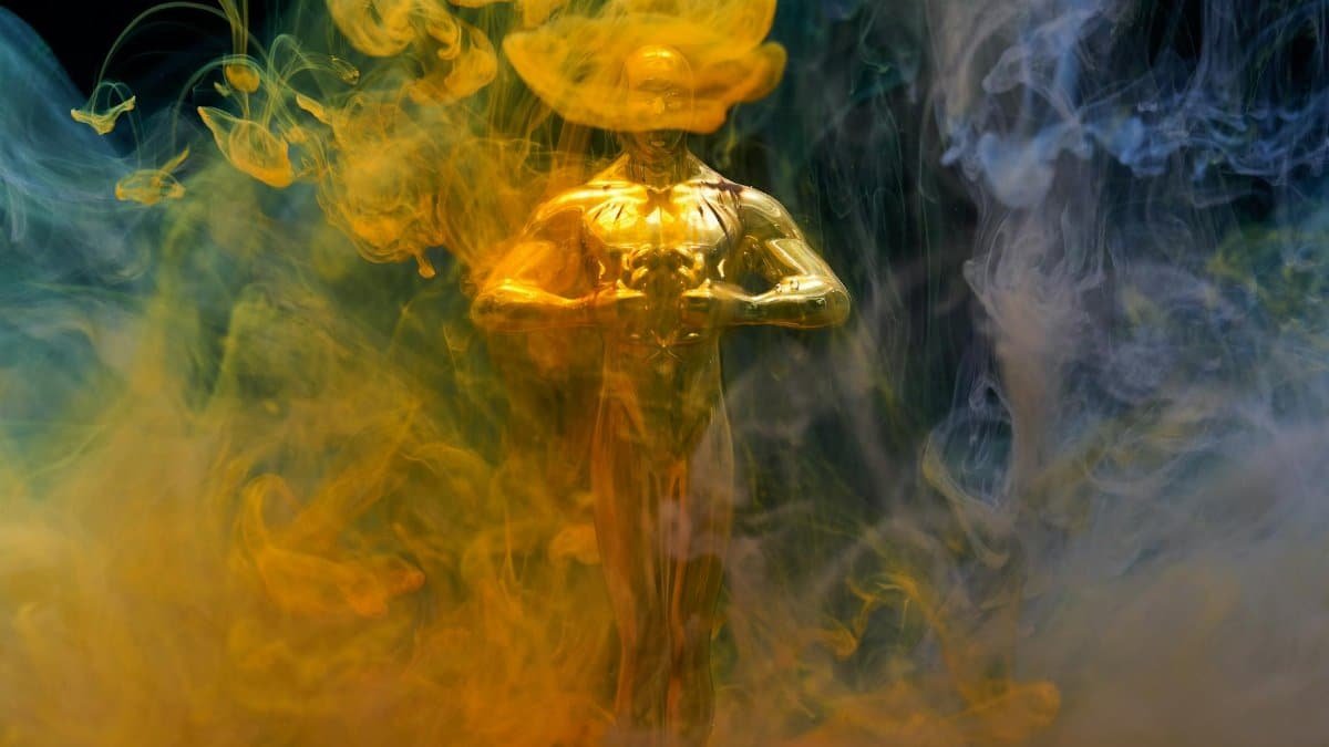 A golden statuette enveloped in vibrant yellow and blue smoke, symbolizing achievement and success.