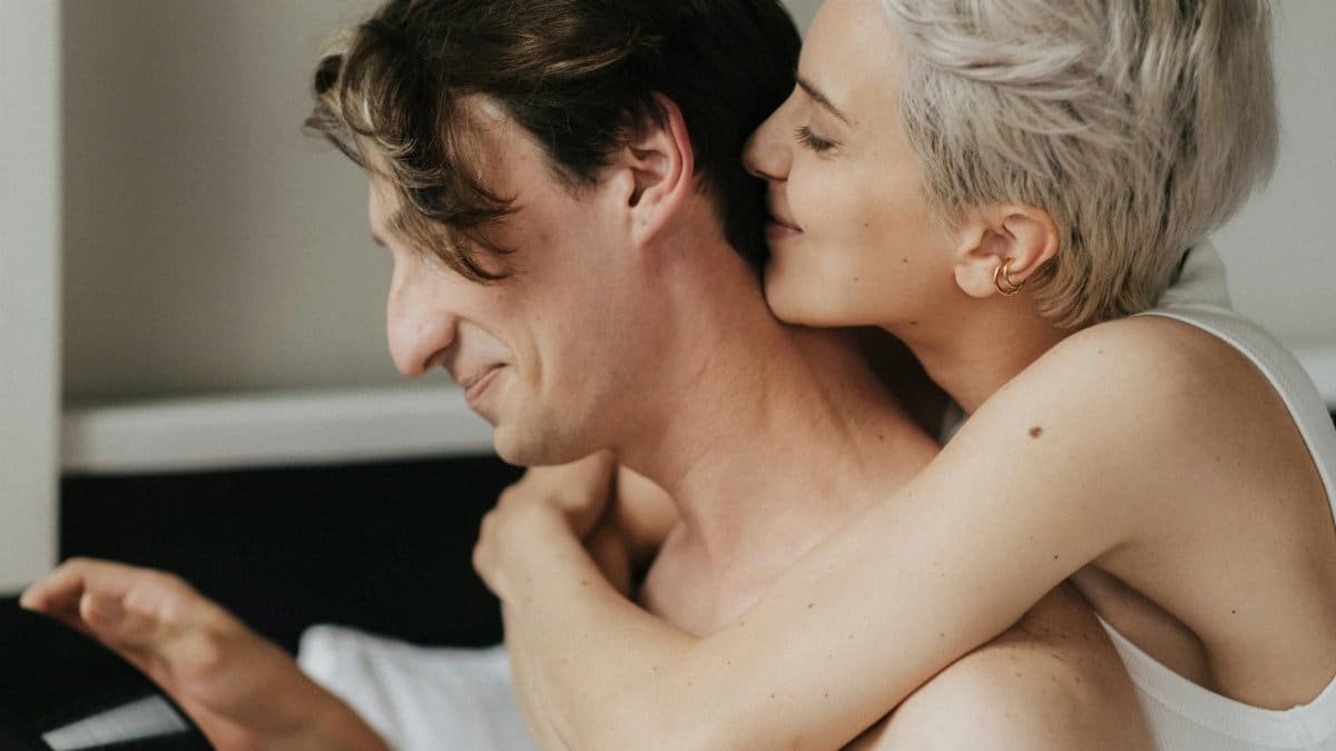 A loving couple embraces tenderly in a cozy indoor setting, showcasing intimacy and connection.