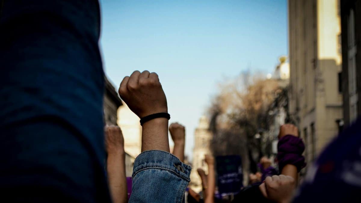 Vivid scene of women raising fists at an outdoor rally, symbolizing empowerment and rights advocacy.