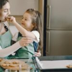 A joyful moment of a mother and daughter baking cookies together in the kitchen.