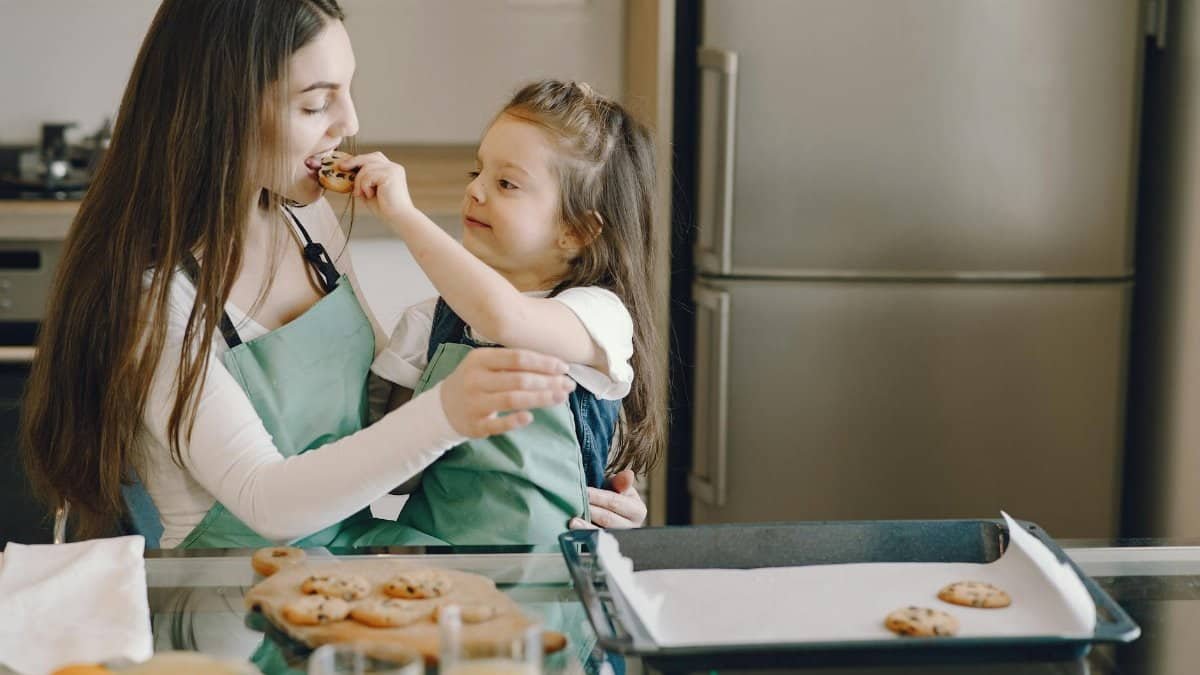 A joyful moment of a mother and daughter baking cookies together in the kitchen.