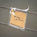 Motivational message on a tag promoting suicide prevention with 'No rain, no flowers' text.