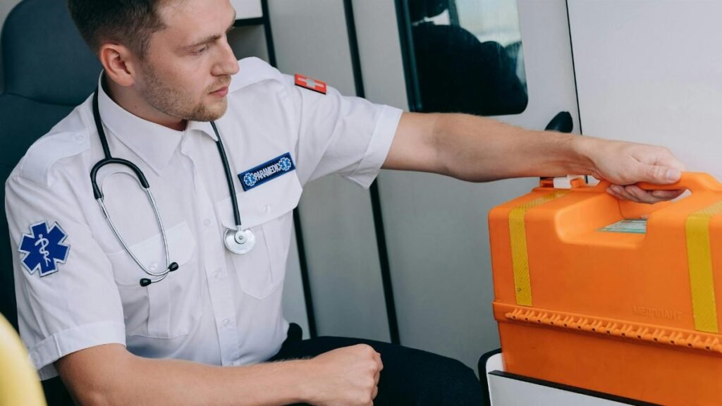 Paramedic sitting in an ambulance with an orange medical kit, ready for emergency response.