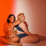 Celebrating diversity and body positivity with two women posing in a vibrant studio setting.