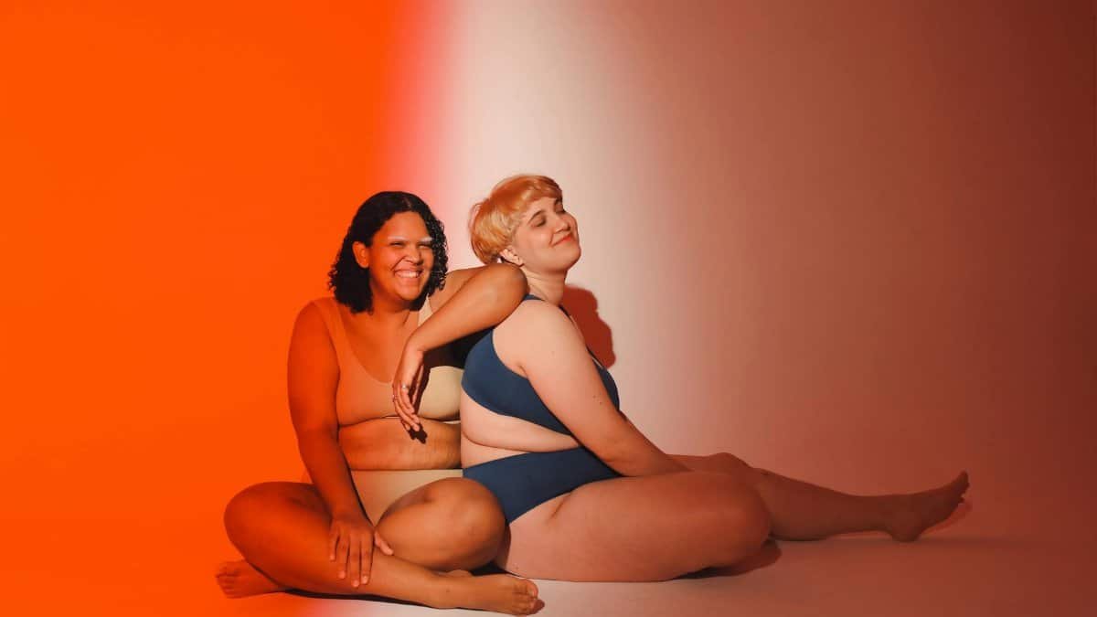 Celebrating diversity and body positivity with two women posing in a vibrant studio setting.
