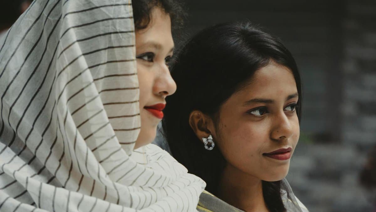 Close-up of two young women with scarves looking afar, exuding confidence and style.
