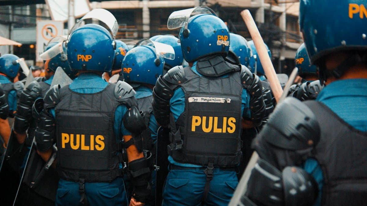 Riot police in blue uniforms and helmets gather for a street demonstration response.