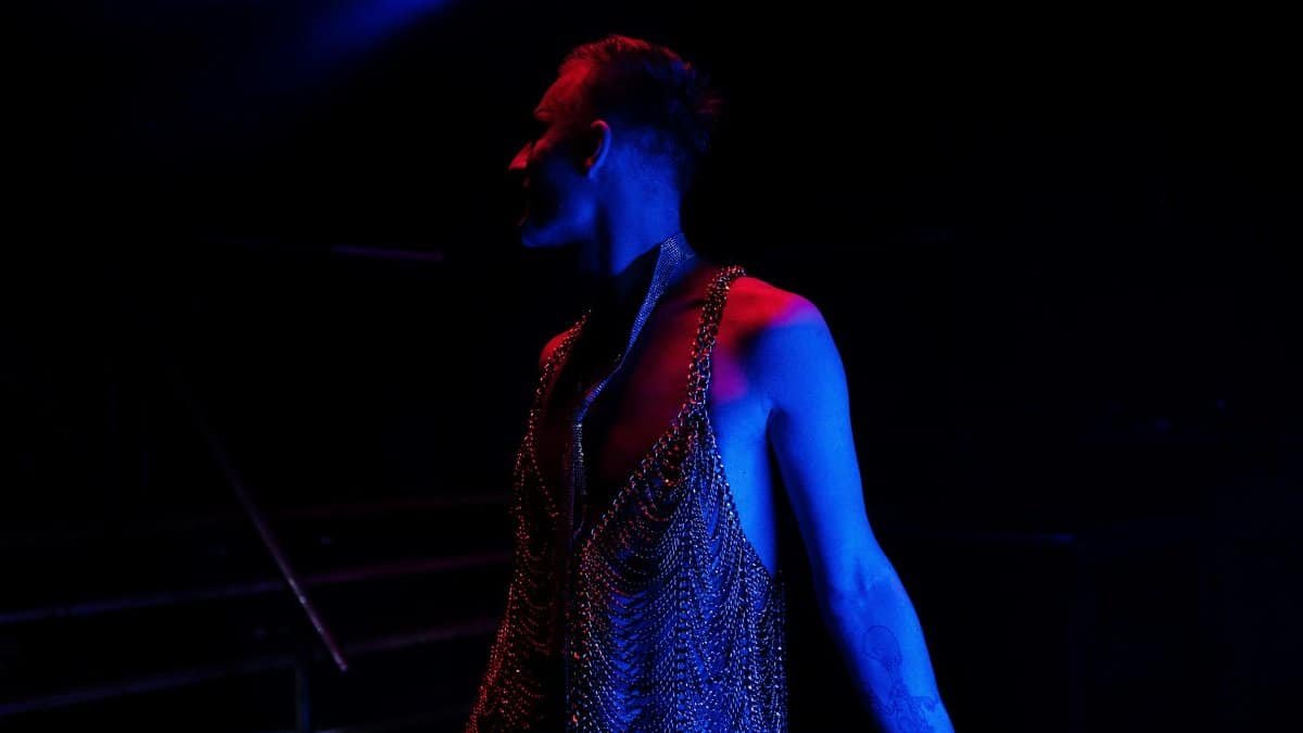 A performer on stage bathed in blue and red spotlight, exuding a vibrant nightlife atmosphere.