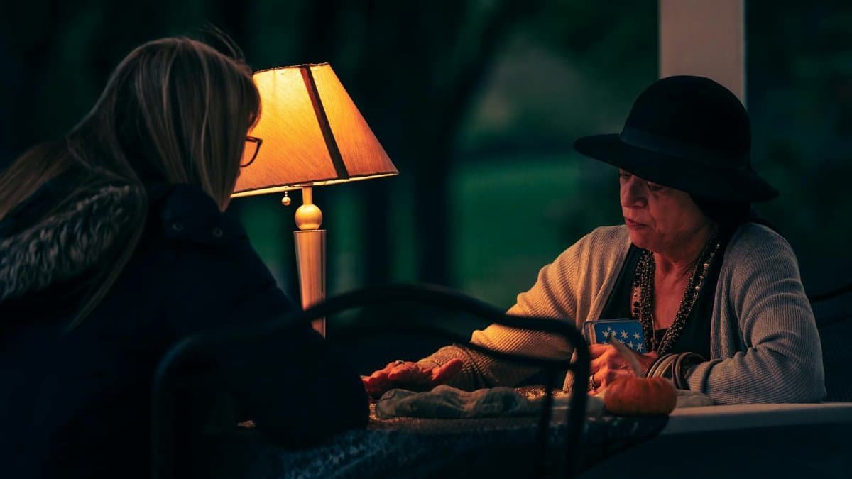 A mysterious tarot reading session between a fortune teller and a woman at night.