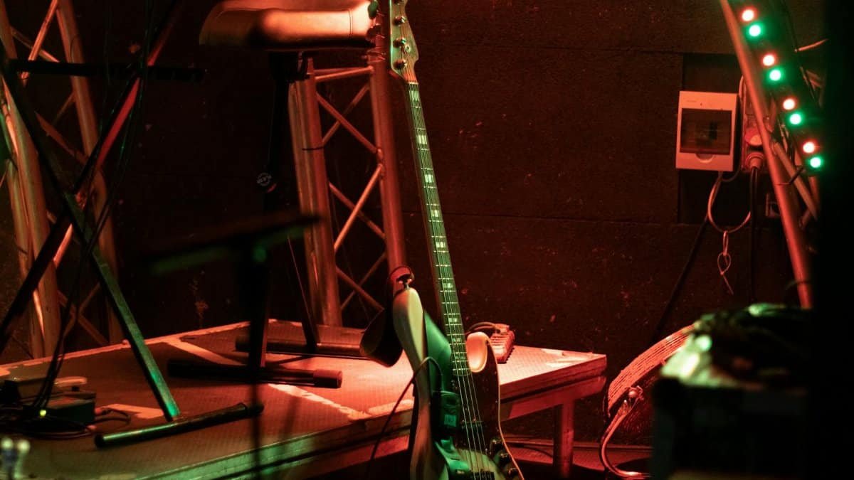 An atmospheric stage with a bass guitar and vibrant strip lights, ready for a live performance.