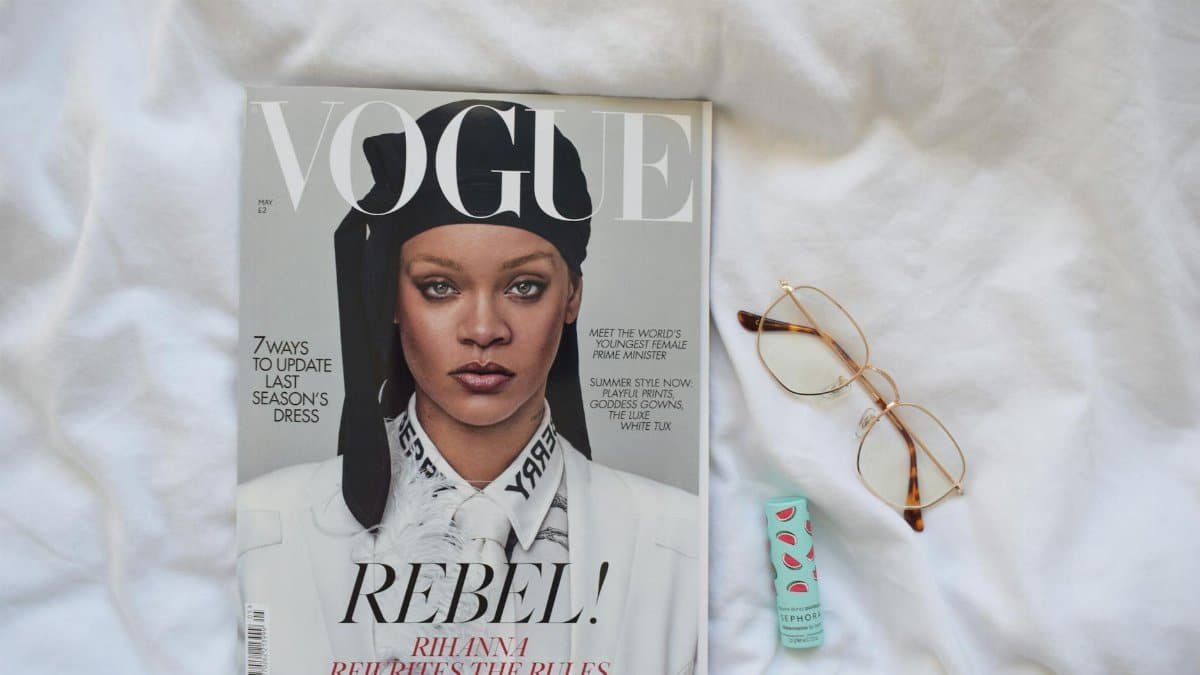 Vogue magazine featuring a celebrity with eyeglasses and lip balm on white fabric.