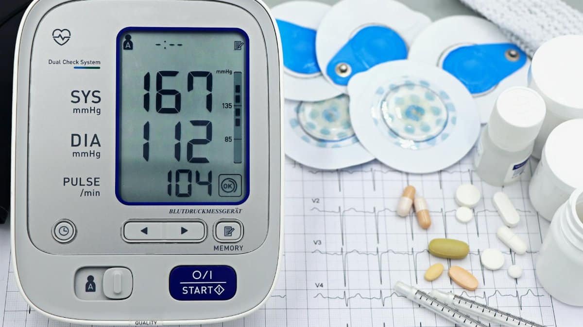 A close-up shot of medical equipment including blood pressure monitor and pills on an ECG graph.